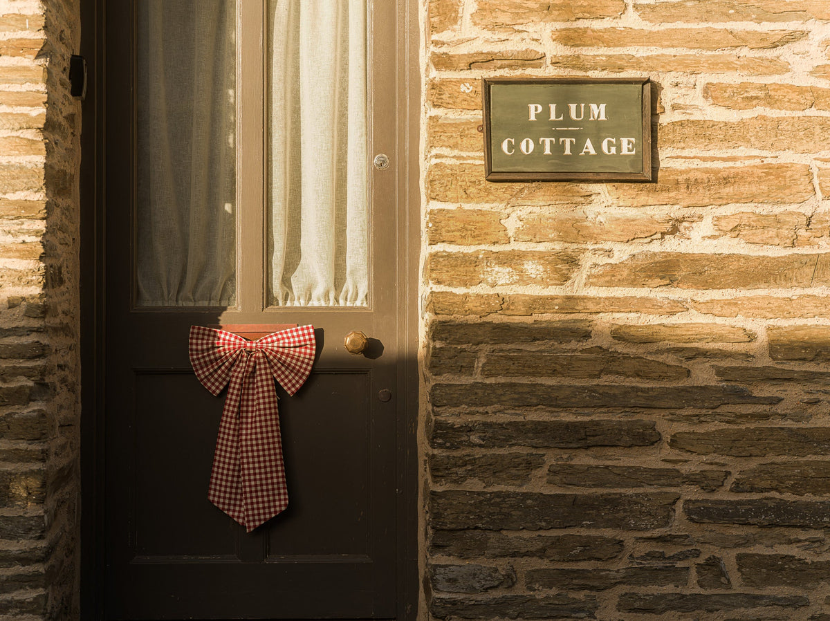 Bow on doorway of an old English brick home called the Plum Cottage.