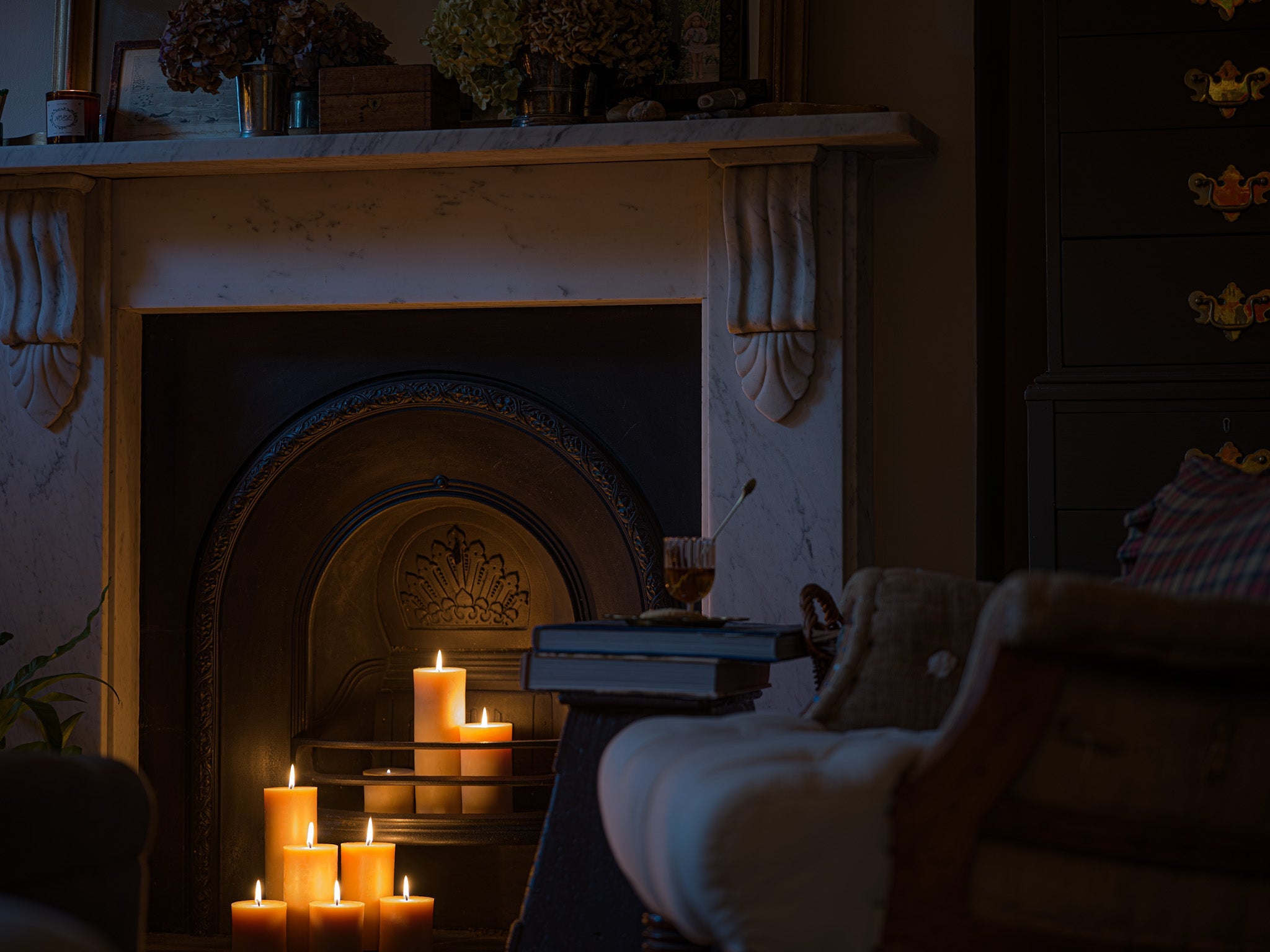 a sofa full of cushions sits in a warm sitting room with a plate of cookies on a nearby footstool