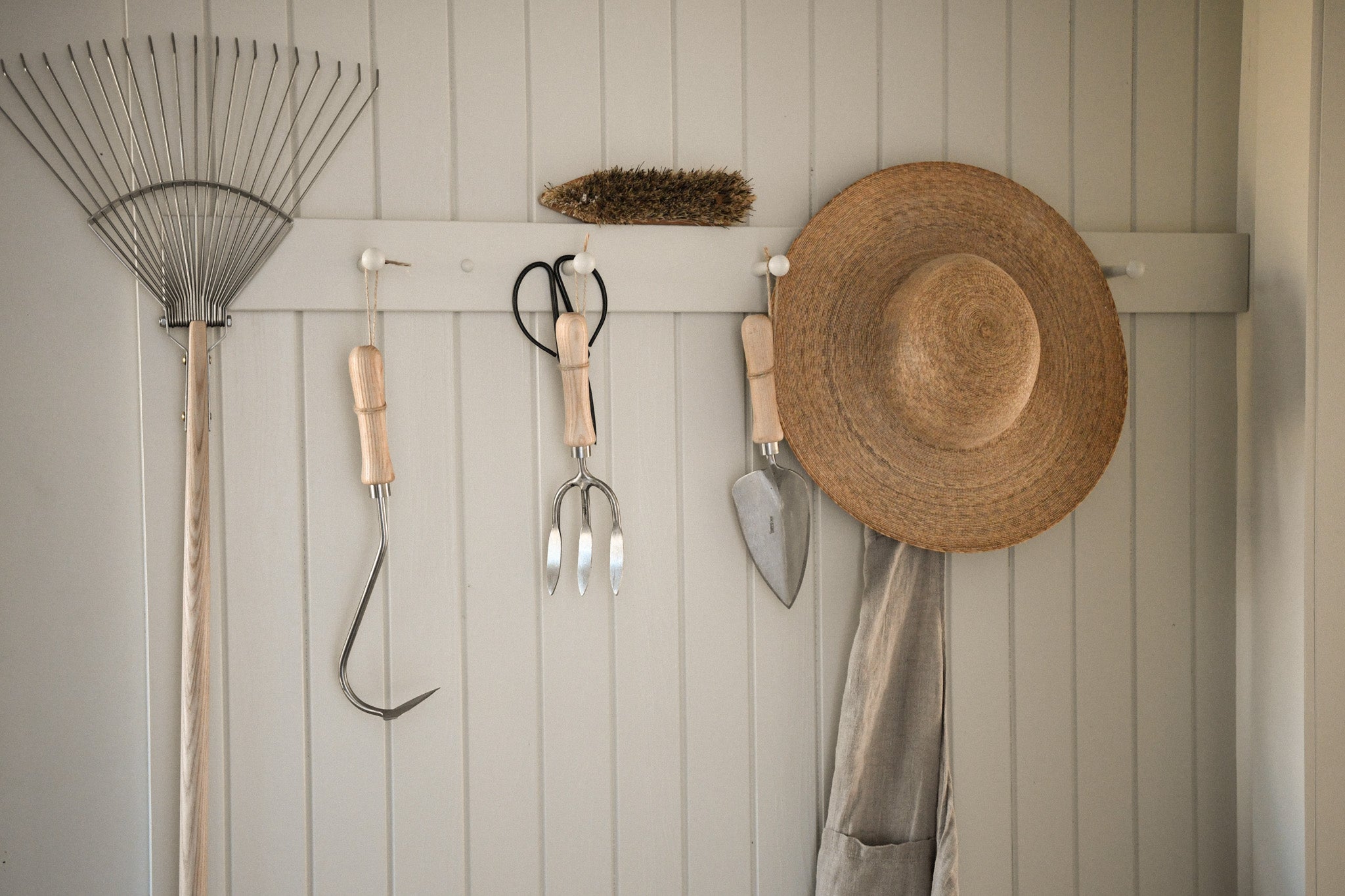 gardening tools hung up on a peg rail 