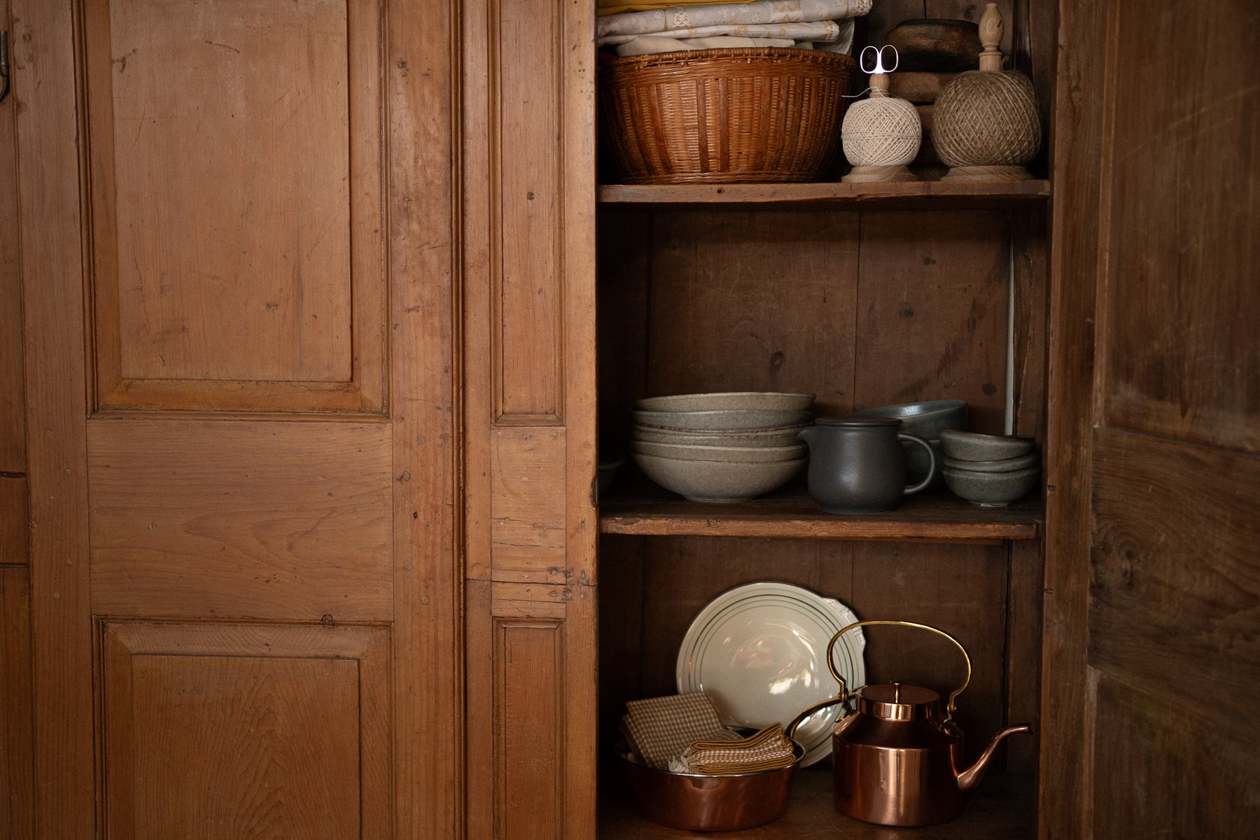 Wooden cabinet with shelves containing various ceramic and metal items.