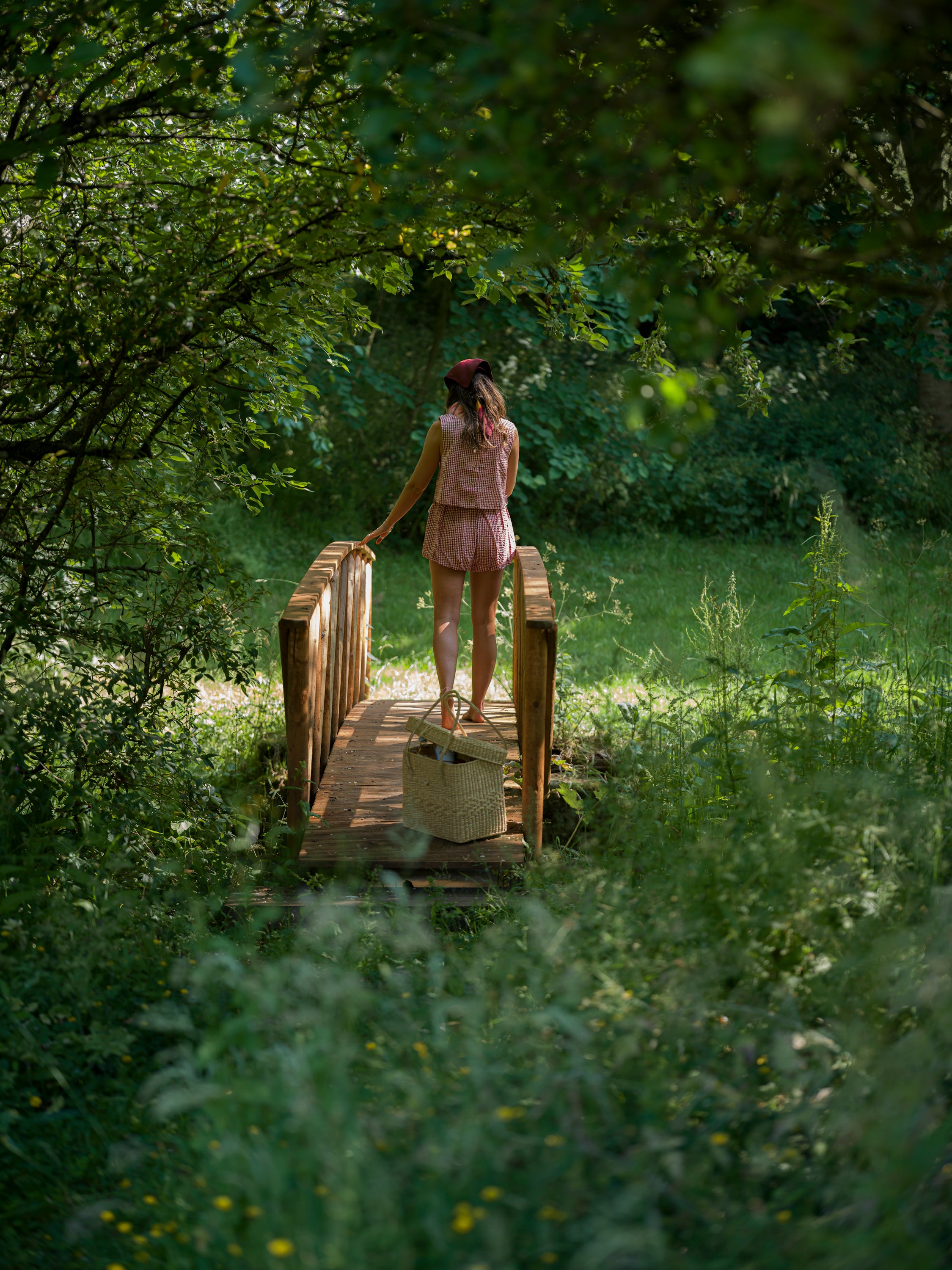 Woman walking across a wooden bridge in a lush green forest
