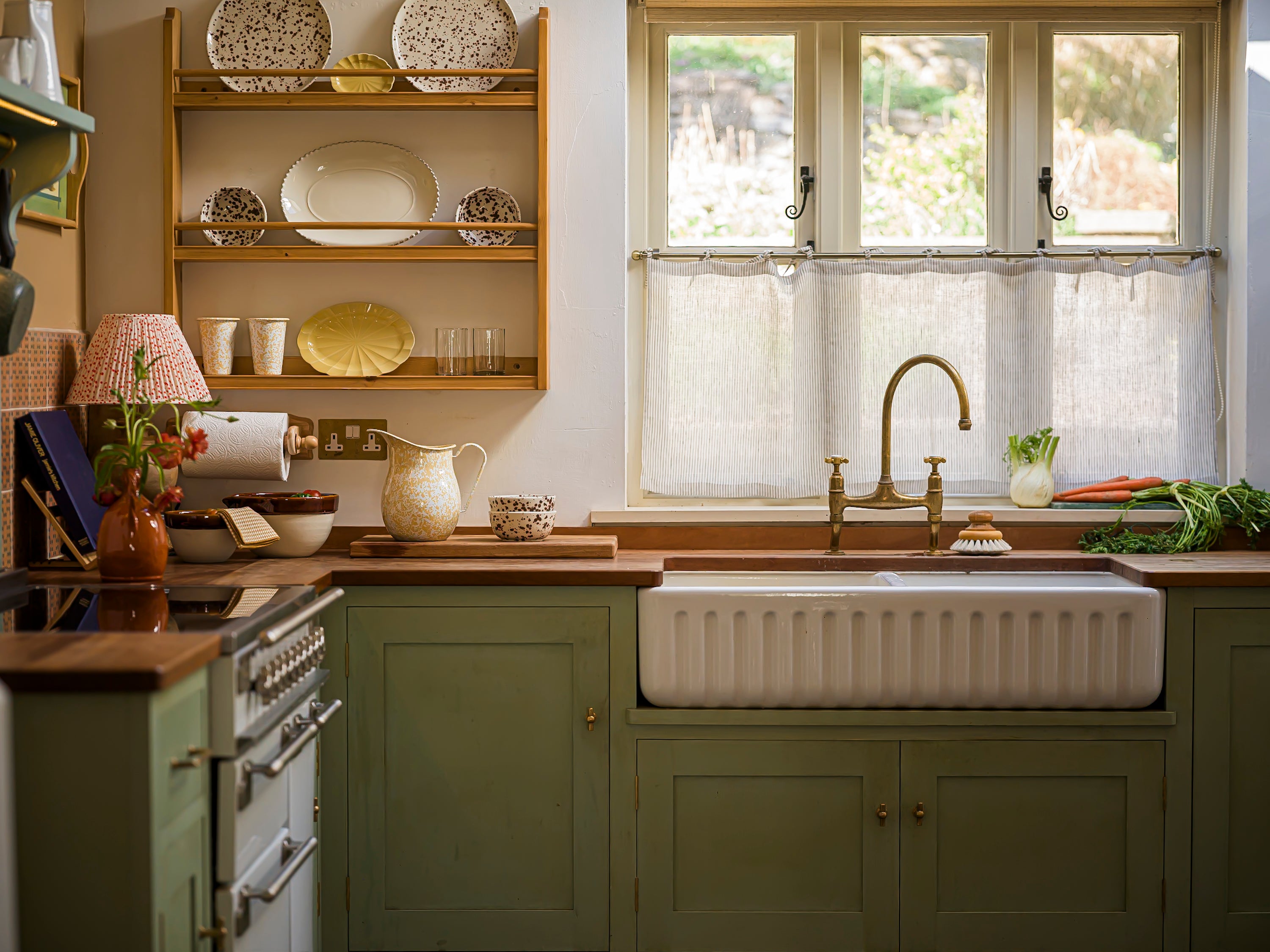Kitchen with wooden shelves, green cabinets, and a window above the sink.