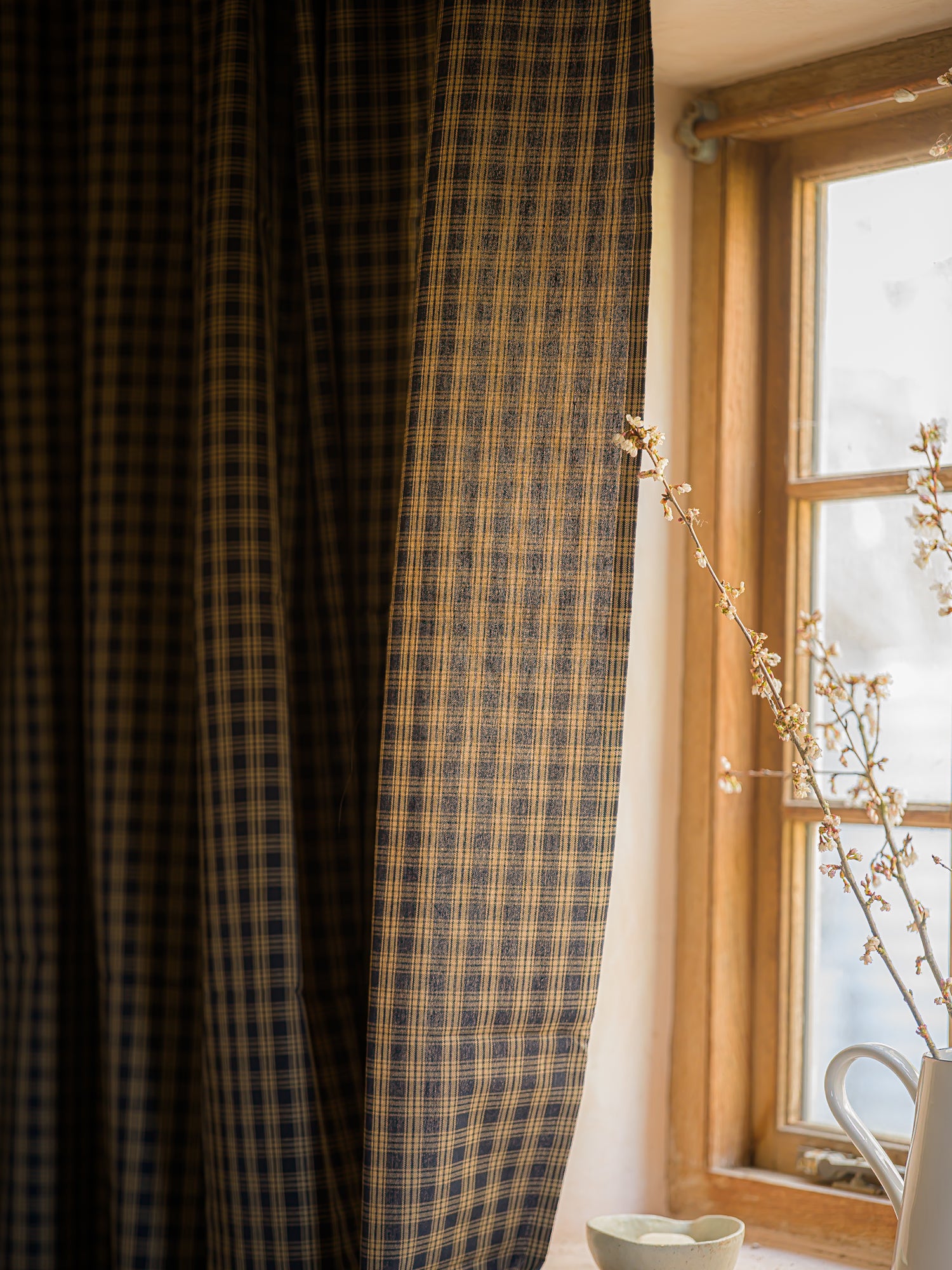 Plaid curtain in front of a window with natural light