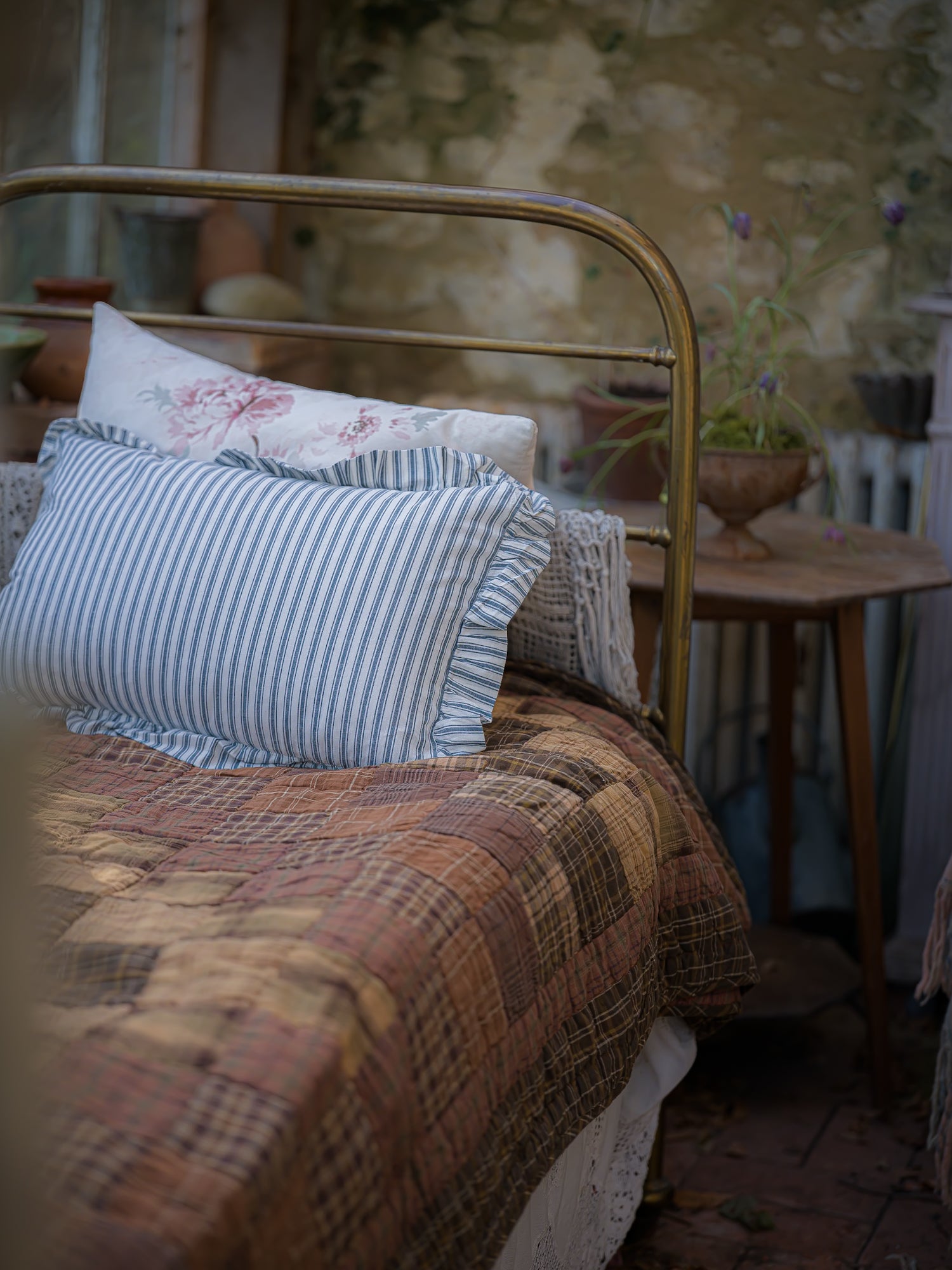 Bed with patterned pillows and quilt in a rustic room setting.
