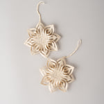 Two natural woven rattan garland ornaments shaped like six-pointed stars, hanging against a light gray background.