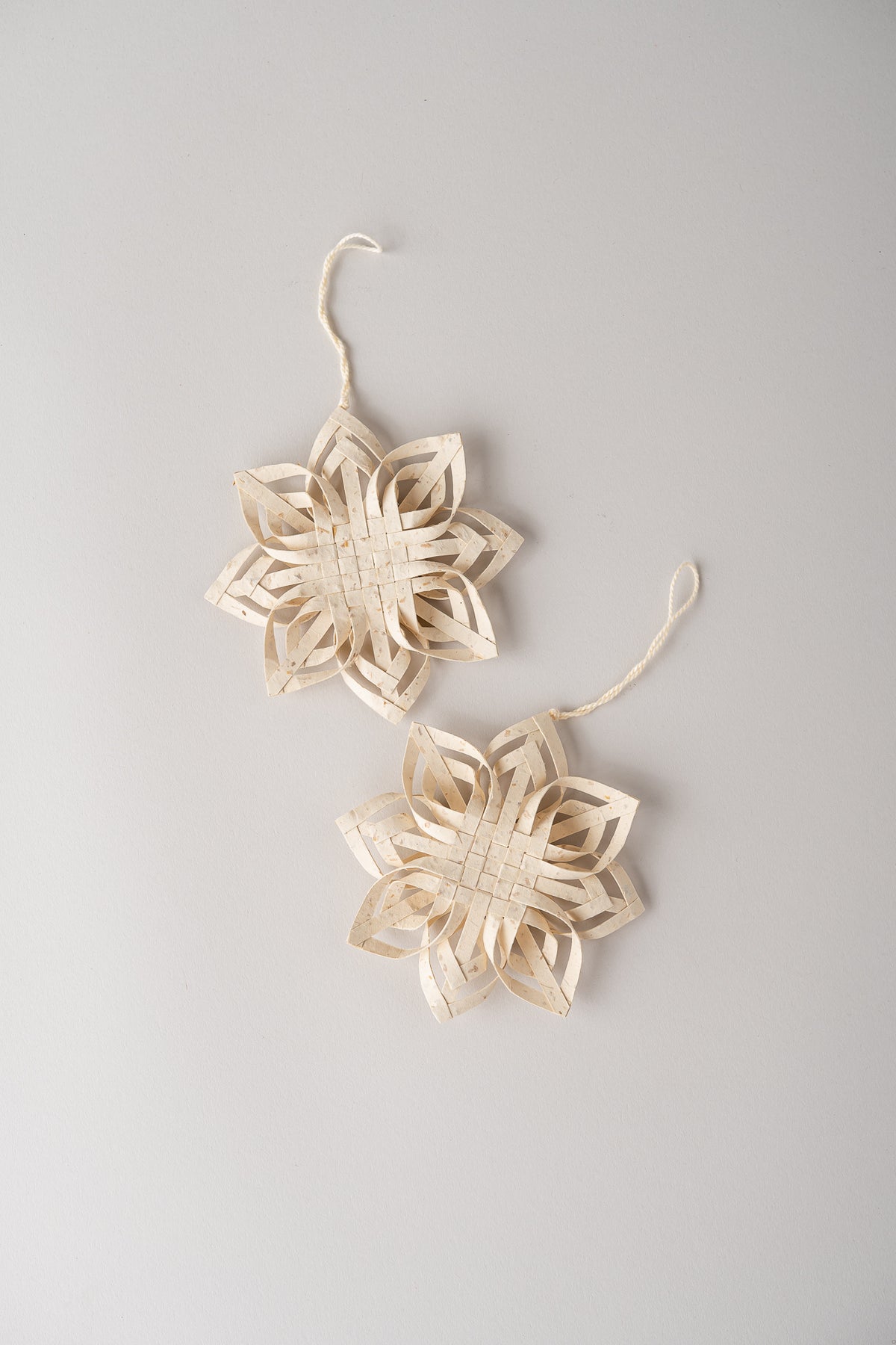 Two natural woven rattan garland ornaments shaped like six-pointed stars, hanging against a light gray background.