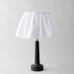 Table lamp with a black base and white shade on a light gray background